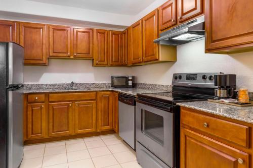 a kitchen with wooden cabinets and stainless steel appliances at Comfort Inn & Suites Chesapeake - Portsmouth in Chesapeake