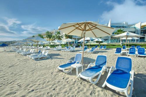 um grupo de cadeiras e um guarda-sol numa praia em Radisson Blu Resort, Fujairah em Dibba