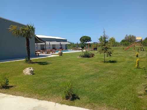 a grassy yard with a playground and a house at Olympia Suites in Pýrgos