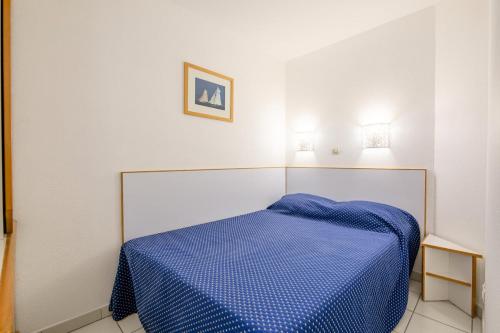 une chambre avec un lit avec une couette bleue dans l'établissement Résidence le Hameau de Cap Esterel - maeva Home - Appartement 2 pièces 4 personnes - Sélection MAE-5654, à Saint-Raphaël