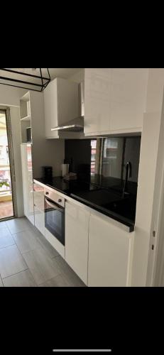 une cuisine avec des armoires blanches et un comptoir noir dans l'établissement Apparement T2 pour 4 personnes, à Cannes