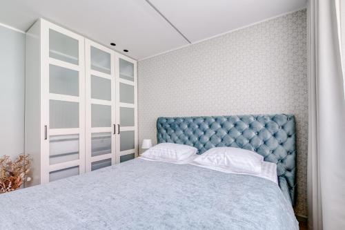 a bedroom with a blue tufted bed with white pillows at Old Town apartment in Haapsalu