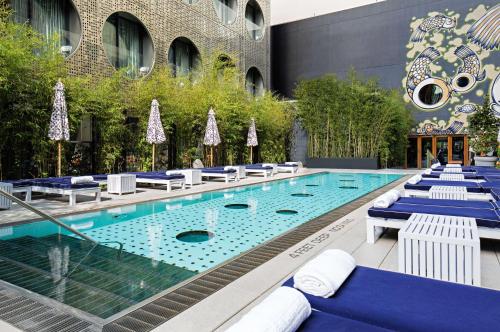 a pool with blue and white chairs and a building at Dream Downtown, by Hyatt in New York