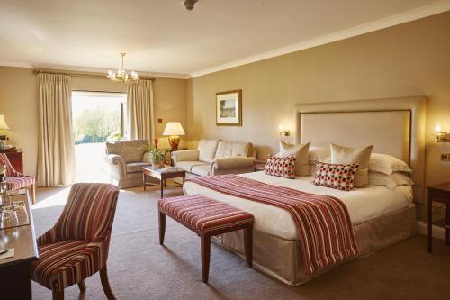 a bedroom with a large bed and a living room at Ashdown Park Hotel in Forest Row