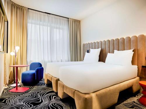 a hotel room with a large bed and a blue chair at TRIBE Milano Malpensa in Vizzola Ticino