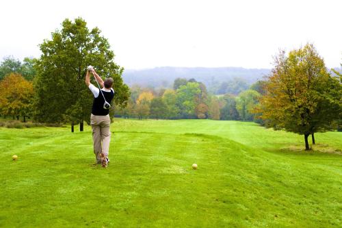 a man swinging a golf club on a green field at Ashdown Park Hotel in Forest Row