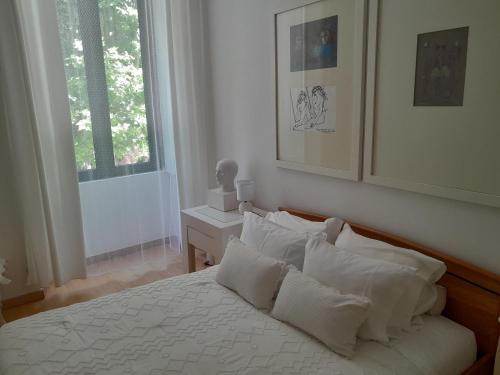 een slaapkamer met een bed met witte kussens en een raam bij Espaco Edla in Sintra