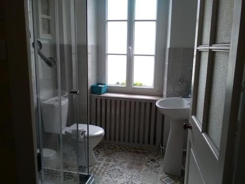 a bathroom with a toilet and a sink and a window at The Old Bakery in Châteauneuf-du-Faou
