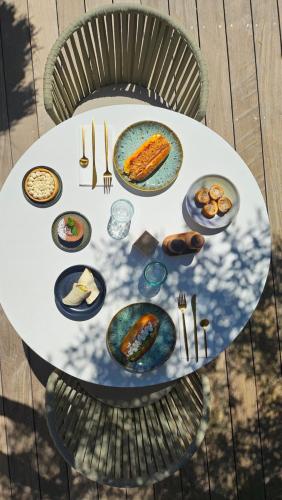 a white table with plates of food on it at H&ocirc;tel Les Suites Du Maquis in Bonifacio