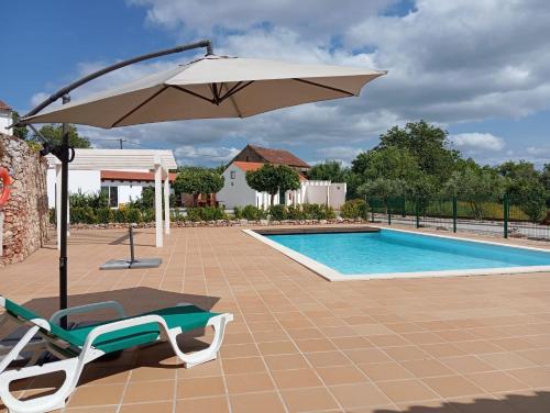 a chair and an umbrella next to a swimming pool at Villa Rominha Alvaiázere - Casa do Rancho in Alvaiázere