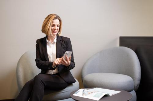 a woman sitting in a chair holding a cell phone at b-smart hotel Widnau in Widnau