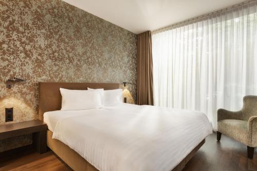 a bedroom with a large white bed and a chair at b-smart hotel Widnau in Widnau