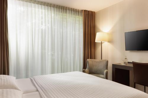 a hotel room with a bed and a chair and a window at b-smart hotel Widnau in Widnau