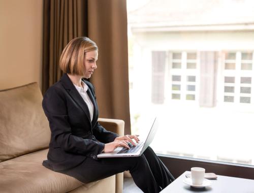 a woman sitting on a couch using a laptop at b-smart hotel Widnau in Widnau