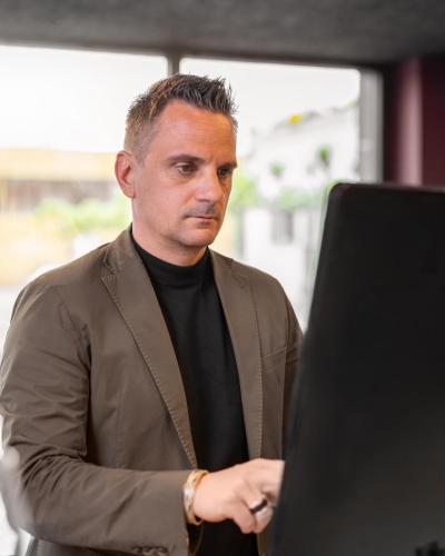 a man standing in front of a laptop computer at b-smart hotel Widnau in Widnau