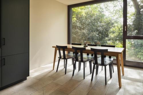 a dining room with a table and chairs and a large window at b-smart hotel Widnau in Widnau