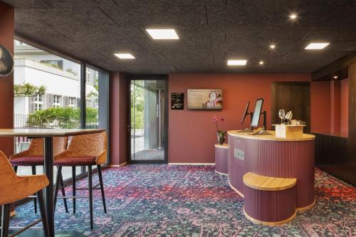 a lobby with orange walls and a table and chairs at b-smart hotel Widnau in Widnau