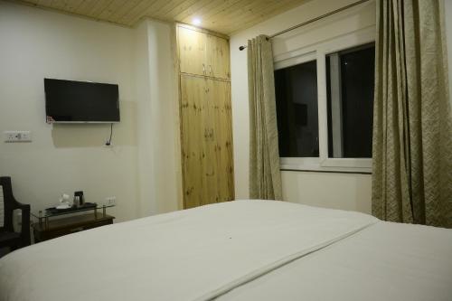 a bedroom with a white bed and a window at Saadhan Homestay in Mussoorie