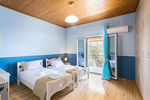 two beds in a room with blue walls and a window at Stavros & Loulas House in Evropoúloi