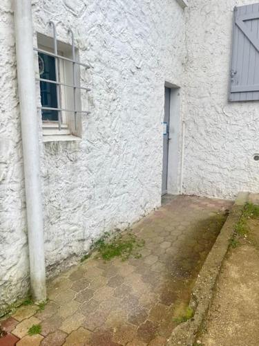 - un bâtiment blanc avec une fenêtre et une porte dans l'établissement Appartement à 400m de la plage avec parking - CAPBRETON, à Capbreton