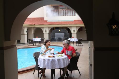 a man and woman sitting at a table in front of a pool at Neonz Resort & Club in Anand