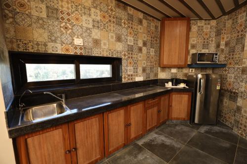 a kitchen with a sink and a stainless steel refrigerator at Neonz Resort & Club in Anand