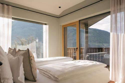 two beds in a room with a large window at ANTON Nature Hideaway in Natz-Schabs