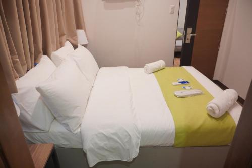 a bed in a hotel room with white sheets and pillows at Avioré Hotel Tacloban in Tacloban