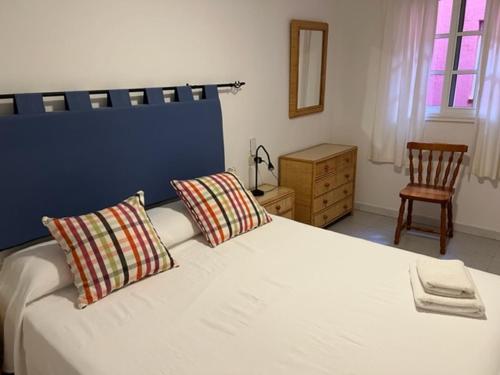a bedroom with a bed with two pillows and a chair at Apartamentos Bellavista Gomera in Playa de Santiago