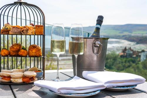 a table with two glasses of wine and a bird cage at Hotel Victoria in Whitby