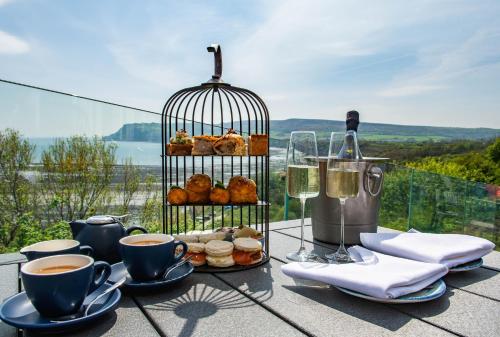 a table with cups of coffee and a bird cage with pastries at Hotel Victoria in Whitby