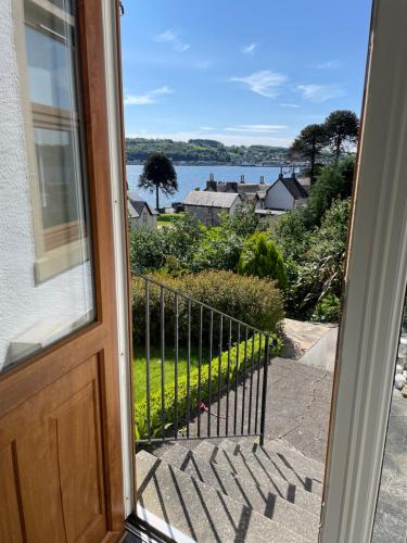 a door to a balcony with a view of the water at Inverbeg Cottage in Rothesay