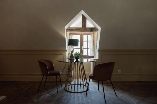 a table and chairs in a room with a window at Manoir de Laroque Delprat in Autoire