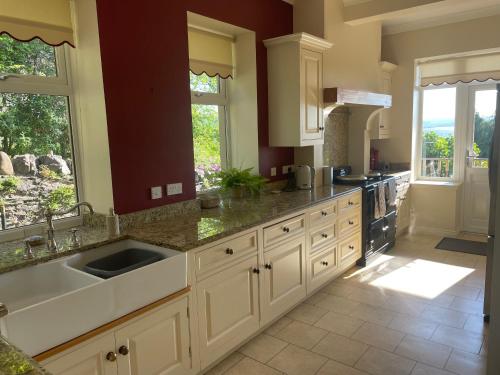 a large kitchen with white cabinets and a sink at Inverbeg Cottage in Rothesay
