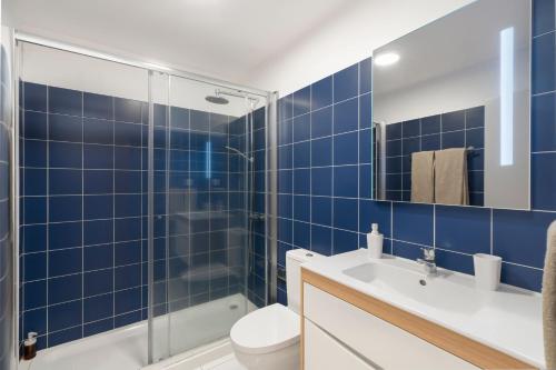 a blue tiled bathroom with a shower and a toilet at OurMadeira - Heart of Old Town I in Funchal