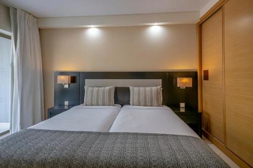 a bedroom with a large bed with two pillows at Areias Village Beach Suite Hotel in Albufeira