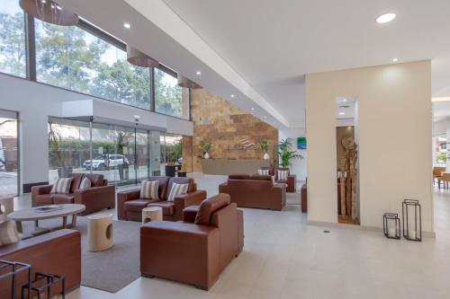 a lobby with couches and tables and windows at Areias Village Beach Suite Hotel in Albufeira