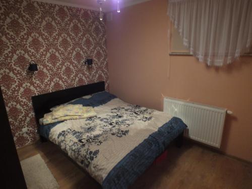 a small bedroom with a bed with a blue blanket at Kaszubski Dworek in Sznurki