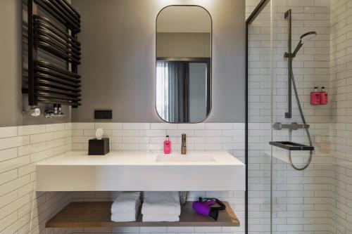 a bathroom with a white sink and a shower at Moxy Warsaw Praga in Warsaw