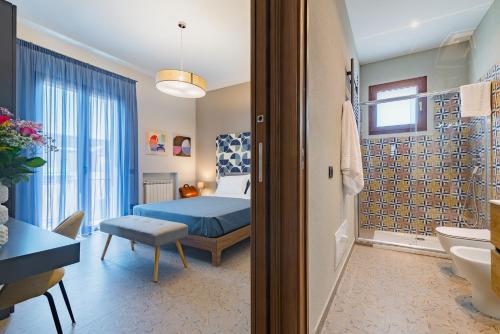 a bedroom with a blue bed and a bathroom at Macramè Suites in Sciacca