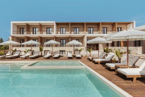 un hotel con piscina, sillas y sombrillas en Verano Afytos Hotel en Afitos