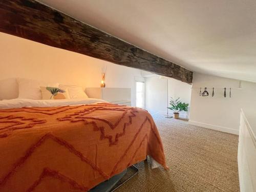 una camera da letto con un grande letto e un piumone arancione di Nid perché en centre historique d'Avignon ad Avignone