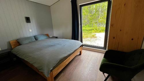 1 dormitorio con cama, ventana y silla en Kesterciema Buki - vacation house in Kesterciems en Ķesterciems