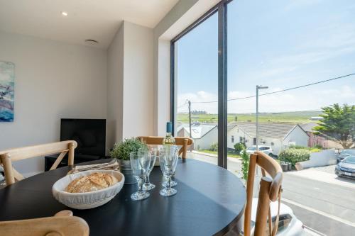 a dining room with a black table and a large window at Bol Y Maer, Bude in Bude