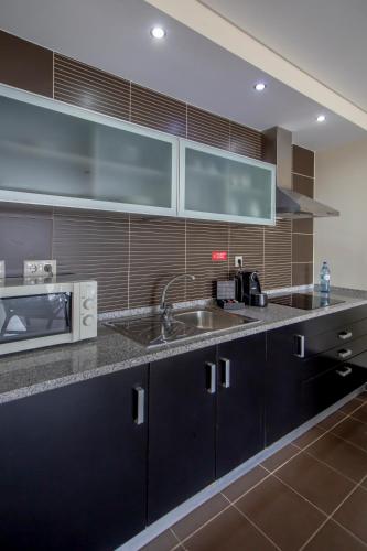 a kitchen with a sink and a microwave at Areias Village Beach Suite Hotel in Albufeira
