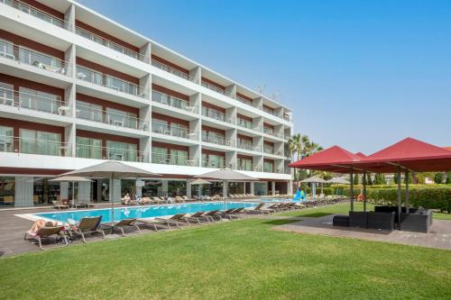 um hotel com piscina, cadeiras e guarda-sóis em Areias Village Beach Suite Hotel em Albufeira