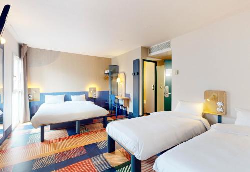 a bedroom with two beds and a room with two tables at B&B HOTEL Nantes Centre in Nantes