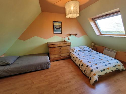 une chambre mansardée avec un lit et une fenêtre dans l'établissement evasion exotique à 700 metres de la plage, à Plouescat