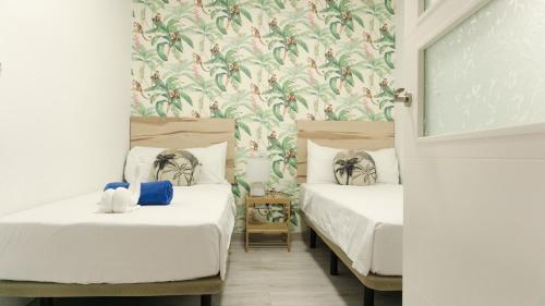 Zwei Betten in einem Zimmer mit Blumentapete in der Unterkunft Agüita Surf Lodge in Las Palmas de Gran Canaria