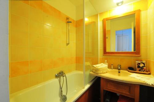 une salle de bain avec une baignoire, un lavabo et un miroir dans l'établissement La résidence du Lac - maeva Home - Appartement cosy avec balcon 2 pièces 4 personnes - Prestige - super Home MAE-6751, à Monflanquin